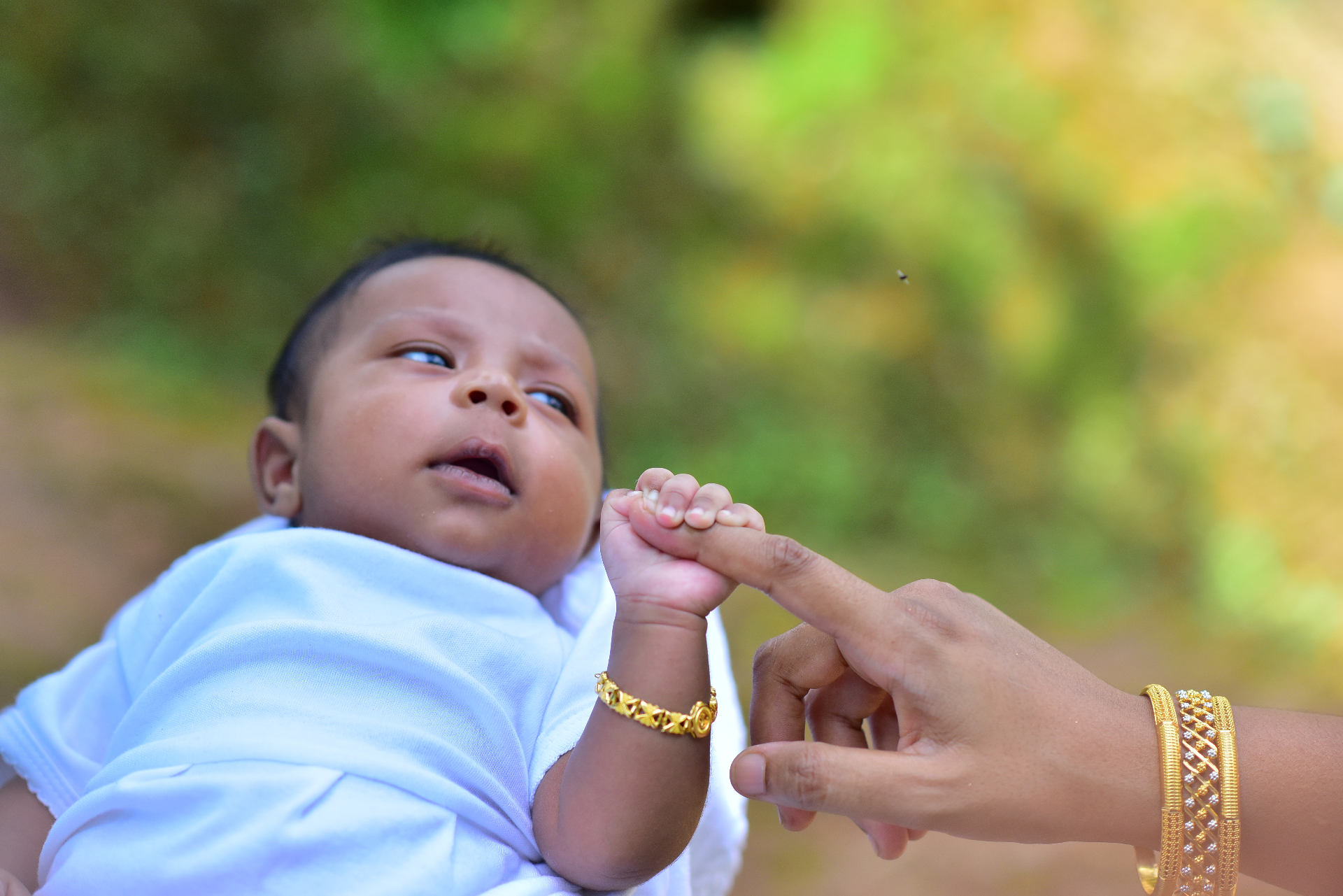 A baby's tiny hand holding a mother's finger